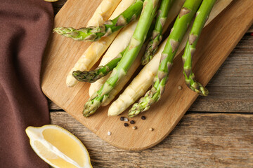 Different raw asparagus spears and spices on wooden table, flat lay