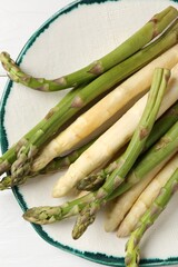 Different raw asparagus spears on white table, top view