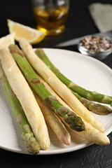 Green and white asparagus with spices on black table, closeup