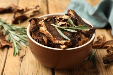 Dried chanterelle mushrooms with rosemary on wooden table, closeup
