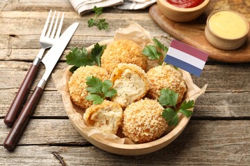 Delicious fried croquette balls, parsley and small flag of Netherlands on wooden table, closeup