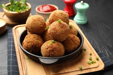 Delicious fried croquette balls with green onion on grey textured table, closeup