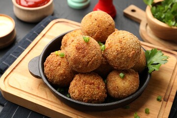 Delicious fried croquette balls with parsley and green onion on grey table, closeup