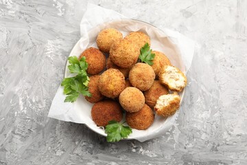 Delicious fried croquette balls with parsley on grey textured table, top view