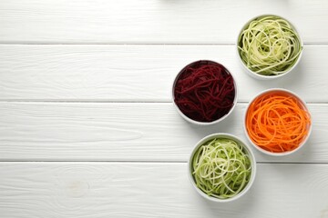 Vegetarian dish. Different vegetable noodles in bowls on white wooden table, flat lay. Space for text