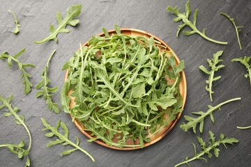 Fresh ripe green arugula leaves on black table, flat lay