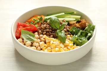 Healthy vegetarian food. Delicious Buddha bowl with lentils, tofu, chickpeas and vegetables on light wooden table, closeup