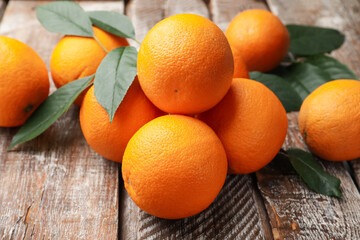 Fresh oranges and leaves on wooden table, closeup