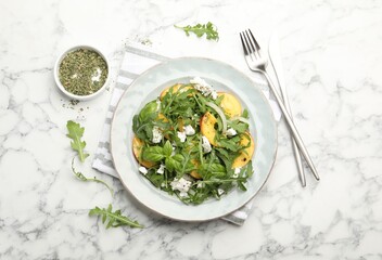 Tasty salad with arugula, cheese, peach, basil and spices on white marble table, flat lay