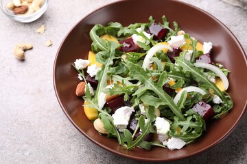 Tasty salad with arugula, cheese, peach, beetroot and nuts on grey table, above view