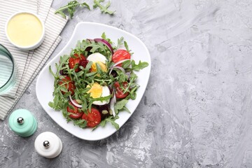 Tasty salad with arugula, vegetables and egg served on grey table, flat lay. Space for text