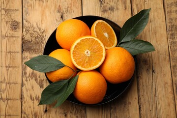Fresh ripe oranges and leaves on wooden table, top view