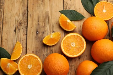 Fresh ripe oranges and leaves on wooden table, flat lay. Space for text