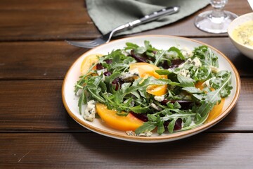 Tasty salad with arugula, blue cheese and vegetables on wooden table, closeup