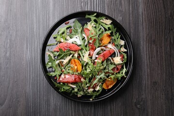 Tasty salad with arugula, cheese, grapefruit, vegetable and balsamic sauce on dark wooden table, top view
