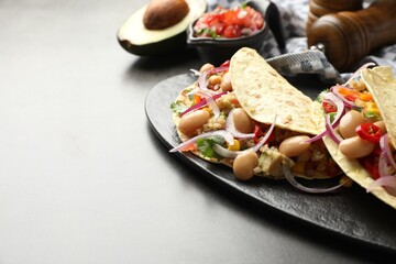 Tasty vegetarian tacos with beans and quinoa served on grey table, closeup. Space for text