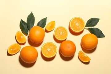 Fresh ripe oranges and green leaves on beige background, flat lay