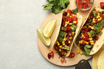 Tasty vegetarian tacos and ingredients on light grey table, flat lay. Space for text