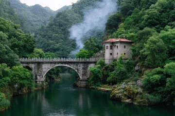 Ancient stone arch bridge spans a serene river amidst lush green mountains with a historic building nearby