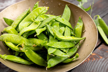 fresh ripe green pea pods in a metal bowl close up