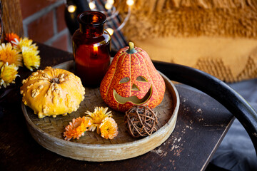Autumn cozy mood composition on the porch. Pumpkins, yellow autumn flowers, candles on the tray