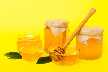 Honey in jar with leaves and honey dipper on colored background top view with copy text