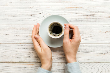 Minimalistic style woman hand holding a cup of coffee on Colored background. Flat lay, top view...