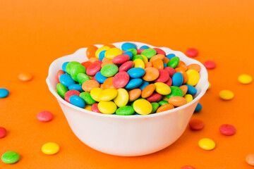 Multicolored candies in a bowl on a colored background. birthday and holiday concept. Top view with copy space