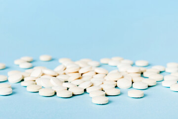Heap of white pills on colored background. Tablets scattered on a table. Pile of red soft gelatin capsule. Vitamins and dietary supplements concept