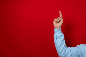 Male hand in blue diver pointing at a copyspace area on a red background, advertising area