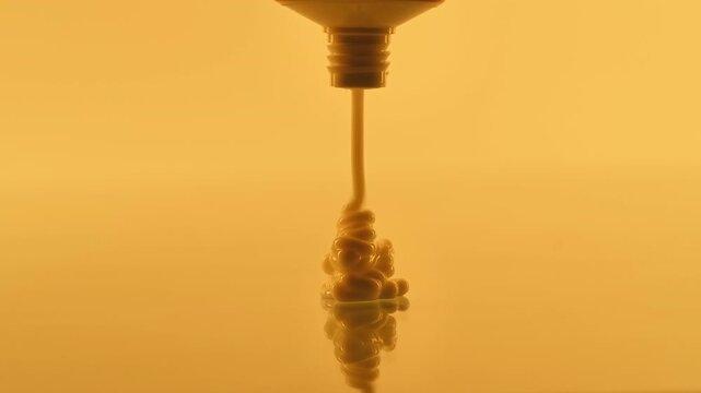 Close-up of Liquid or Cream Being Dispensed in Warm Light