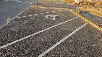 Fototapeta premium Handicapped Parking Space with Worn Asphalt and Roadside Weeds