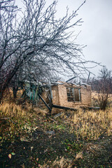 an old, ruined clay house with debris and other debris scattered around it, against a stormy sky