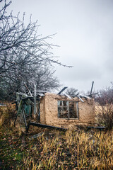 an old, ruined clay house with debris and other debris scattered around it, against a stormy sky