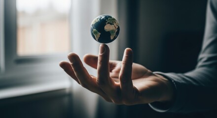 Miniature Earth Globe Balanced on Fingertip Against a Softly Lit Window