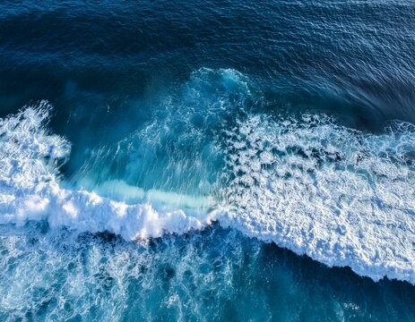 aerial view of ocean waves crashing with white foam on deep blue water creating dynamic sea patterns and textures