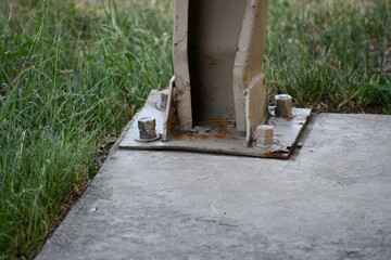 Steel beam bolted to concrete. Damaged steel support beam for outdoor picnic structure.