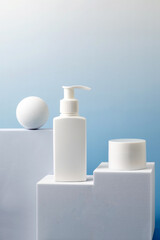 a set of unbranded white containers with cream, lotion or other cosmetics on a catwalk on a blue gradient background.Mockup