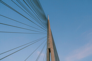 Minimalist view of a modern cable-stayed bridge against clear blue sky, looking up from below