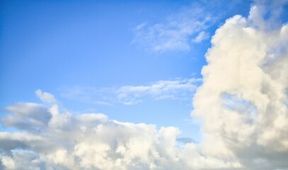 Sky replacement of some light grey puffy clouds with a light blue sky behind them.