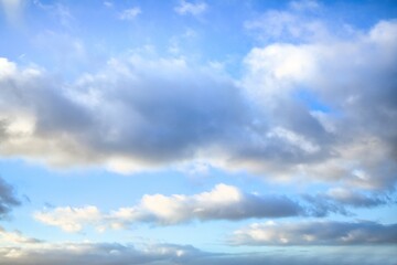 Sky replacement of some light grey puffy clouds with a light blue sky behind them.