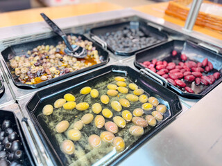 A delightful selection of marinated olives in black trays, featuring green, black, and red varieties, ideal for enhancing a gourmet buffet with rich flavors.