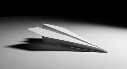 A simplistic paper airplane resting on a gray surface with a dark background and soft lighting shown