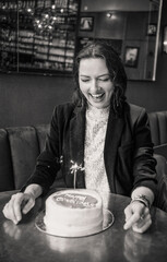 Smiling woman holding a birthday cake with a sparkler