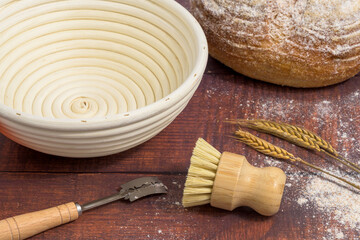 Sourdough bread making proofing basket loaf and brush on a wooden table