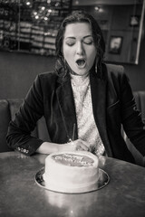 Woman Blowing Out Candles on a Birthday Cake