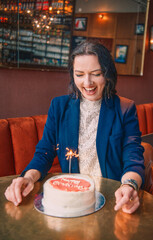 Smiling woman holding a birthday cake with a sparkler