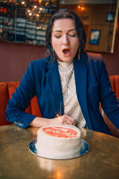 Woman Blowing Out Candles on a Birthday Cake