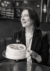 Smiling woman holding a birthday cake with a sparkler