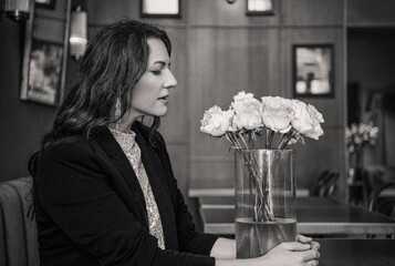 Smiling woman with flowers in a cafe, black and white portrait